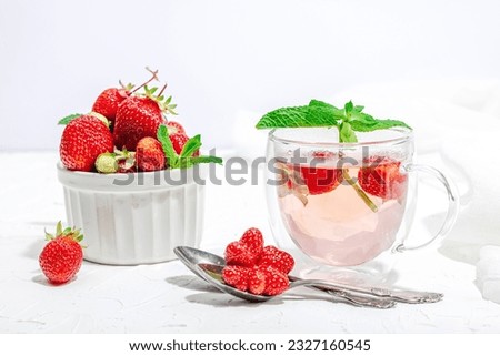 Strawberry tea concept. Good morning concept. Teapot, ripe fruits, healthy beverage. Hard light, dark shadow, white background, close up