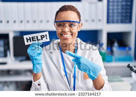 Beautiful african american woman working at scientist laboratory asking for help smiling happy pointing with hand and finger 