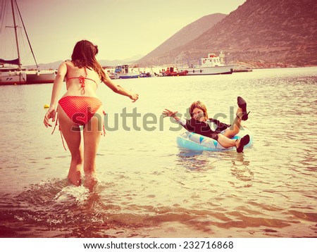 Young woman in bikini gives hand to businesswoman in ocean during holiday summer vacation 