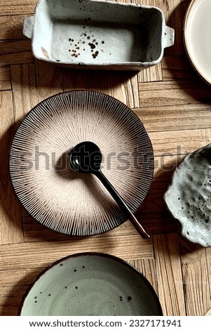 Table situation. Brown handmade ceramic plate with spoon on wooden table or background. Flat lay photography