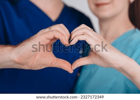 heart sign, two hands of young caucasian man and woman in blue clothes folded in heart gesture, love and tenderness concept, background
