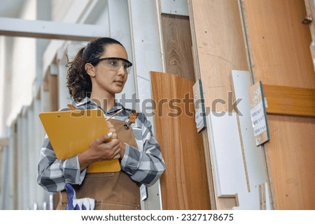 staff working in wood furniture industry factory checking inventory of plywood wooden board type material in stock wood store warehouse. Royalty-Free Stock Photo #2327178675