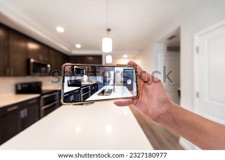Hand photographing house apartment kitchen island room for sale or rent with phone smartphone closeup point of view in modern luxury condo home with blurry bokeh background Royalty-Free Stock Photo #2327180977