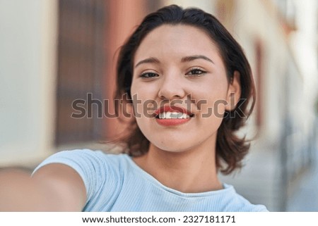Young hispanic woman smiling confident making selfie by camera at street