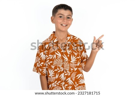 Little hispanic boy wearing hawaiian shirt looking at camera indicating finger empty space sales