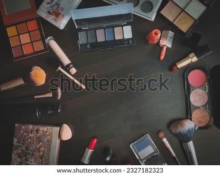 Decorative cosmetics and makeup brushes on a black wooden background. Top view.