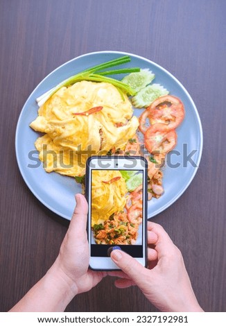 Top view of woman hands using smartphone to taking photo of Asian street food for posting and sharing food pictures on social media 