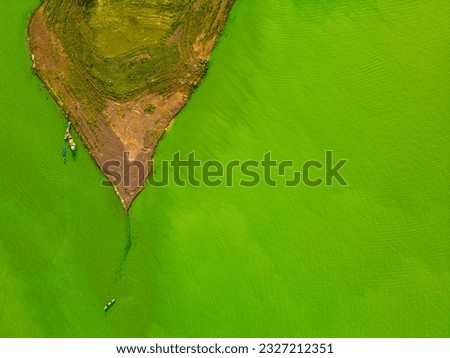 Aerial view of Ben Nom fishing village, a brilliant, fresh, green image of the green algae season on Tri An lake, with many traditional fishing boats anchored. Location in Dong Nai province, Vietnam
