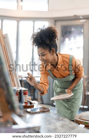 african american female artist painting on canvas doing some art projects on her studio workshop