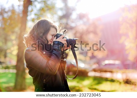 Professional woman photographer taking outdoor portraits with prime lens at sunset, during a sunny day