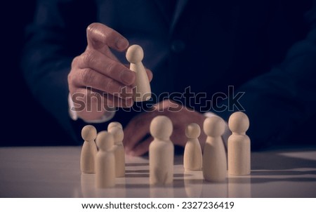 Human resource management concept.HR manager hand or Employer chooses or takes wood people in hand as new employee. Leader stands out from crowd. Looking for good worker. HR, HRM, HRD concept