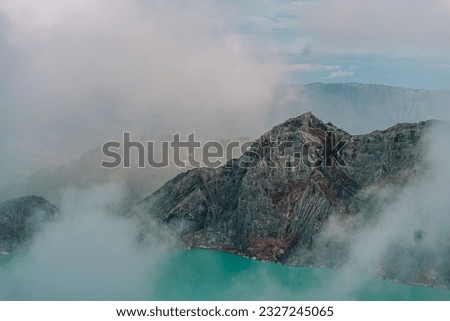 Scenic view of misty mountain and blue lake. Hill landscape and lagoon through the fog