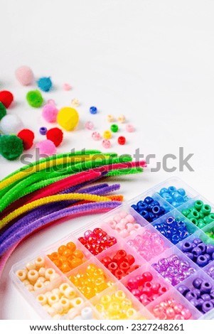 Set for children's crafts. Pipe Cleaners, beads and colorful pom-poms. Different multi-colored supplies and materials for DIY art activity for kids. Motor skills, creativity and  hobby. Royalty-Free Stock Photo #2327248261