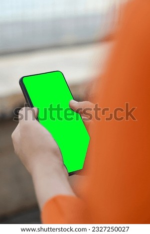 A woman with a green-screened phone in her hand. Space for the image. Green screen for content.