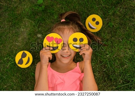 Comely pleasant girl covers the eyes with funny and loving emoticons. A person tries on different personalities