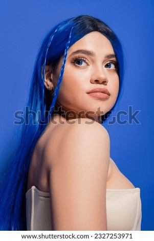 beauty photography, young woman with dyed hair posing on blue background, hair color, glowing skin, female model with makeup and trendy hairstyle, vibrant youth, skin perfection