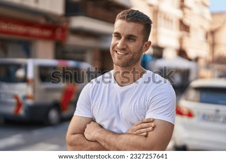 Young caucasian man standing with arms crossed gesture at street