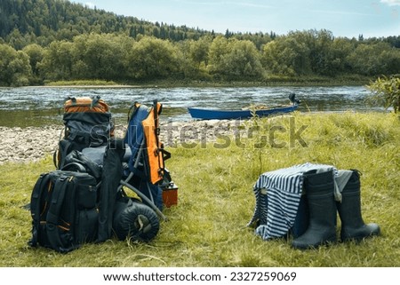 Camping equipment, backpacks, boots lie on the river bank. High quality photo