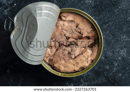 Open tin can with cod liver on wooden table background, close up, top view