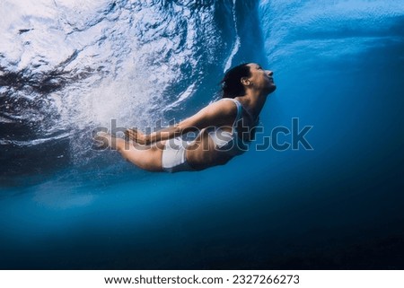 Surfgirl dive without surfboard underwater with ocean wave. Duck dive under barrel wave