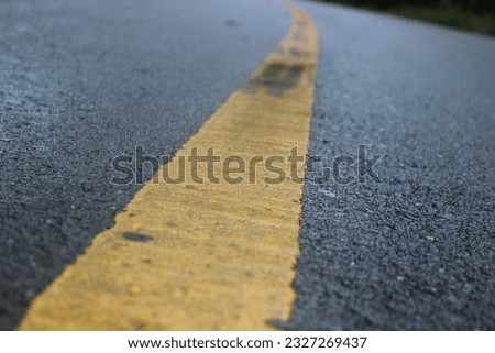 Yellow road marking in the middle of asphalt road