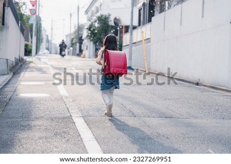 An elementary school girl carrying her school bag to school Royalty-Free Stock Photo #2327269951