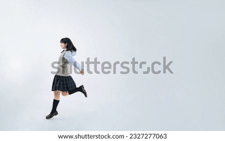 Female student in uniform to jump in white background. Wide angle visual for banners or advertisements.