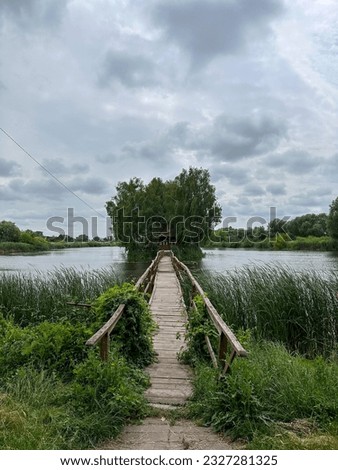 Picturesque mystical fisherman hut cabin with a bridge on a lonely fairy island of love in a beautiful lake cloudy landscape in Solotvin village, vertical photo