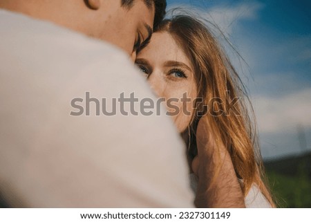 Close-up view of a fashionable young couple kissing, posing in a romantic scenery. Smile, happy woman and man hug in relax environment.