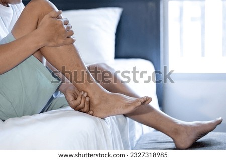 Asian middle aged man suffering from shin splints or medial tibial stress syndrome and achilles tendinitis,inflammation of muscle,acute pain in shin and leg caused by prolonged running,physical injury Royalty-Free Stock Photo #2327318985