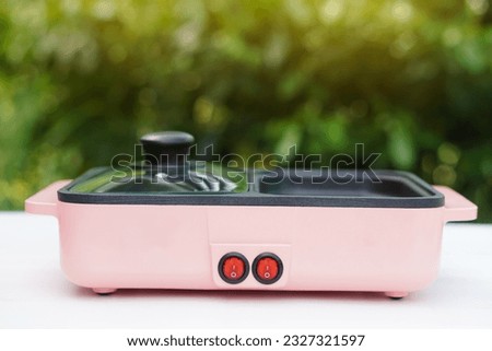 Minimal pink electric pan, placed outdoor. Concept, kitchen utensil. Modern or kitchenware appliances for cooking, can use for grill, boil or fry. Easy to cook.                          Royalty-Free Stock Photo #2327321597