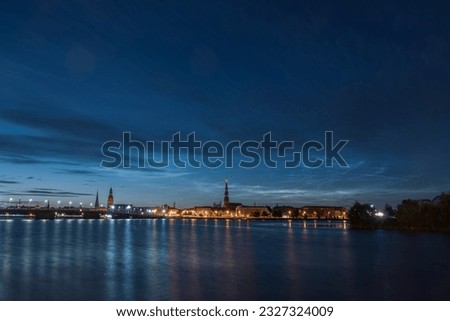 Noctilucent clouds over the Daugava river and view to Old Riga Town and stone bridge on July night. Long exposure photography.