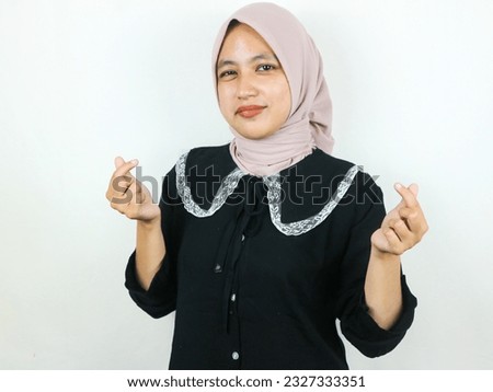 Portait smiling young muslim woman showing heart gesture with both hands.