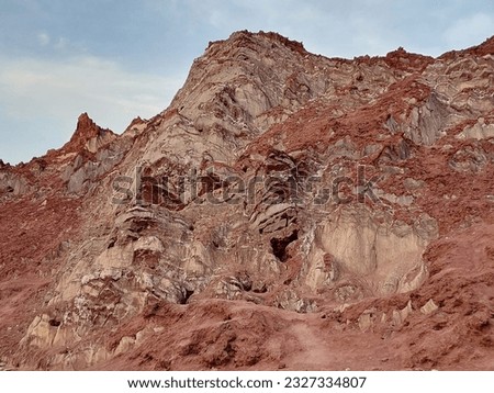 A landscape of red, brown and white salt mountain with blue sky background