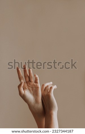 tender hands of the girl are raised up on a plain background. Vertical photo