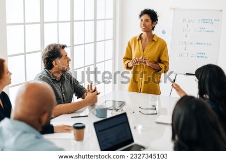 Woman having a discussion with her business team in a boardroom. Black business woman leading a meeting in an office. Female project manager giving a speech to a group of professionals. Royalty-Free Stock Photo #2327345103