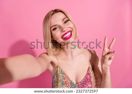 Selfie photo of cute girl showing v-sign greetings symbol hello from christmas party wear festive dress isolated on pink color background
