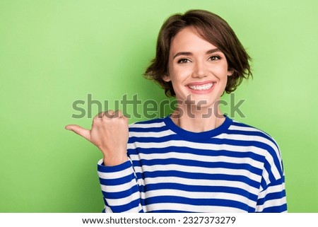 Photo of young beautiful manager pointing finger empty space mockup news wear blue striped shirt isolated green color background
