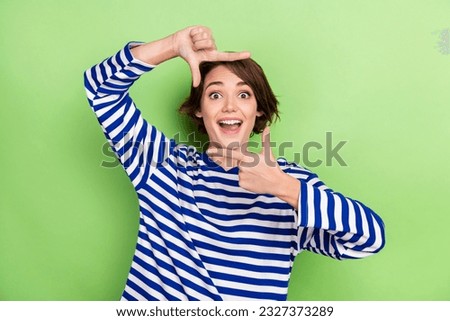 Portrait of astonished ecstatic woman with bob hairdo wear striped sweatshort hands making shot isolated on green color background