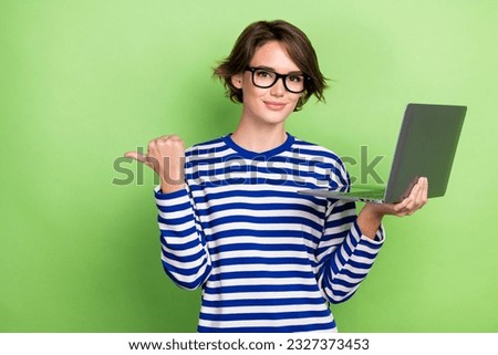 Photo of confident young lady pointing finger empty space hold laptop dell new marketing campaign isolated on green color background