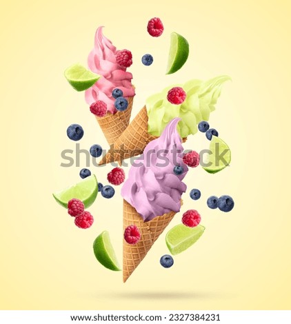 Delicious different ice cream in crispy cones, raspberries, blueberries and pieces of lime falling on beige background