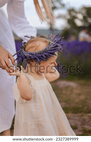 This is a picture of a little girl in a lavender wreath surrounded by her mother