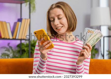 Planning family budget. Smiling young brunette woman counting money cash, use smartphone calculate domestic bills at home room. Girl satisfied of income and saves money for planned vacation, gifts