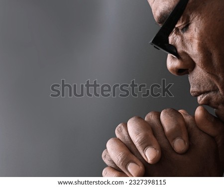 black man praying to god with hands together Caribbean man praying stock photo	
