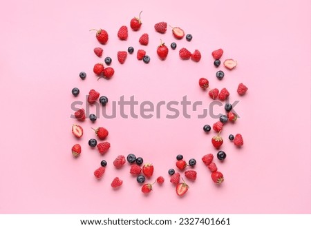 Frame made of fresh raspberries, blueberries and strawberries on pink background Royalty-Free Stock Photo #2327401661
