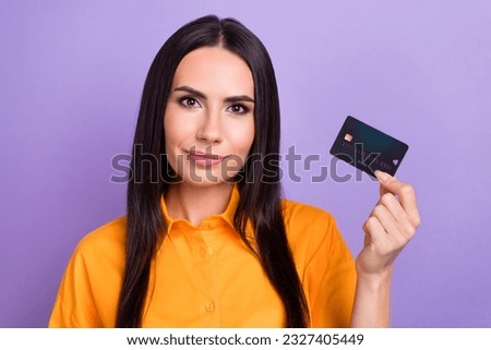 Photo of young promoter brunette hair lady wear orange shirt hold plastic debit payment card want shopping isolated on purple background