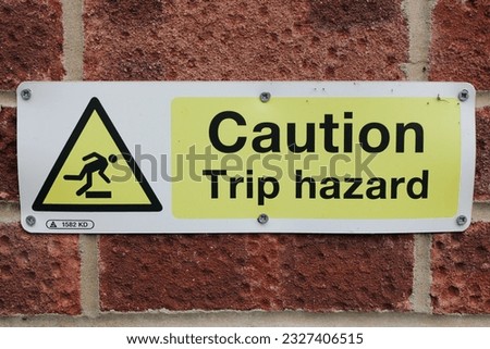 Yellow sign "Caution Trip Hazard" with trip hazard symbol