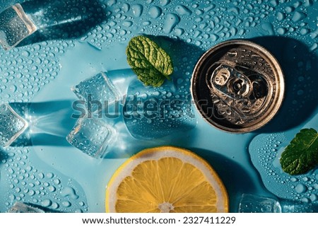 Creative summer composition with lemon slice, mint leaves, can of soda and ice cubes. Top down minimal lemonade drink concept.