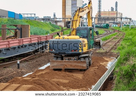 A powerful wheeled excavator prepares the site for the construction of the railway. Excavator with a wide bucket leveling the surface of the railway track. Excavation Royalty-Free Stock Photo #2327419085