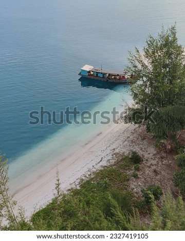 a boat that is leaning on a beautiful island with blue sea water and white sand

